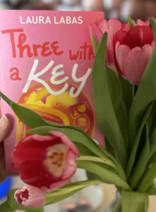 Seitlich neben einer pinken Tulpe ist das ebenfalls knallpinke Cover des Buches zu sehen.