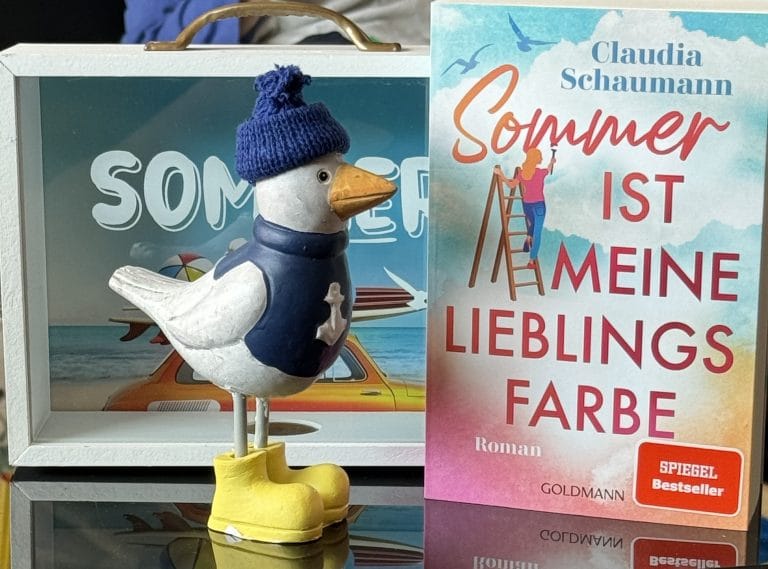 Eine Porzellan-Möwe sieht sich das Cover des Buches an. Darauf ist der Titel des Buches in pink zu sehen und daneben eine gezeichnete Frau auf einer Leiter.