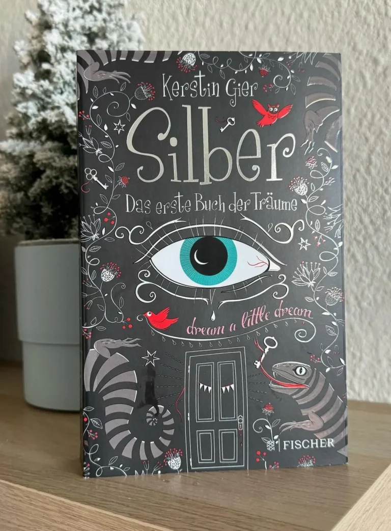 Das schwarz-silberne Cover ziert ein großes gezeichnetes blaues Auge über einer Tür, sowie ein Salamander unten rechts.