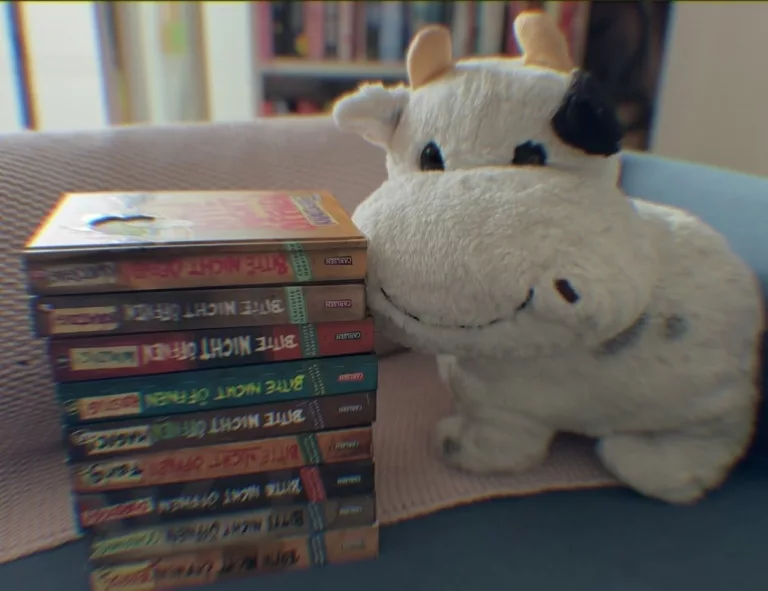 Die 8 Bände aus der Reihe "Bitte nicht öffnen" liegen aufeinander gestapelt auf einem blauen Sofa.