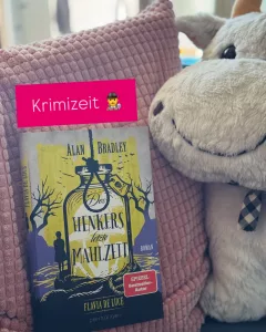 Auf dem gelb-blauen Cover von Alans Bradelys "Des Henkers letzte Mahlzeit" ist eine zugeschraubte Flasche mit stilisierten Pilzen und einem Totenkopf zu sehen, Daneben sieht man Flavias Silhouette mit dem Rücken zu uns gedreht.