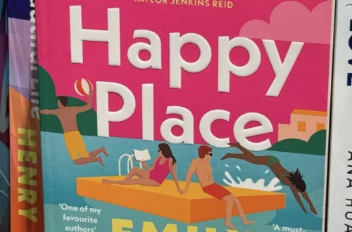 Auf dem Cover sieht man einen pinken Himmel und türkisblaues Meer. Mittig sitzen zwei Protagonisten auf einer schwimmenden Platform und zwei weitere springen gerade ins Meer.