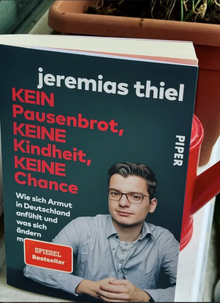 KEIN Pausenbrot, KEINE Kindheit, KEINE Chance 1 Das Cover des Buches „Kein Pausenbrot, keine Kindheit, keine Chance“ von Jeremias Thiel lehnt an einer roten Gießkanne. Auf dem dunkelblauen Cover ist der Autor Jeremias Thiel mit Brille und hellblauem Hemd vor einer weißen Backsteinwand zu sehen. Der Titel ist in großen, roten und weißen Buchstaben gedruckt. Ein roter Aufkleber kennzeichnet das Buch als „Spiegel Bestseller“.